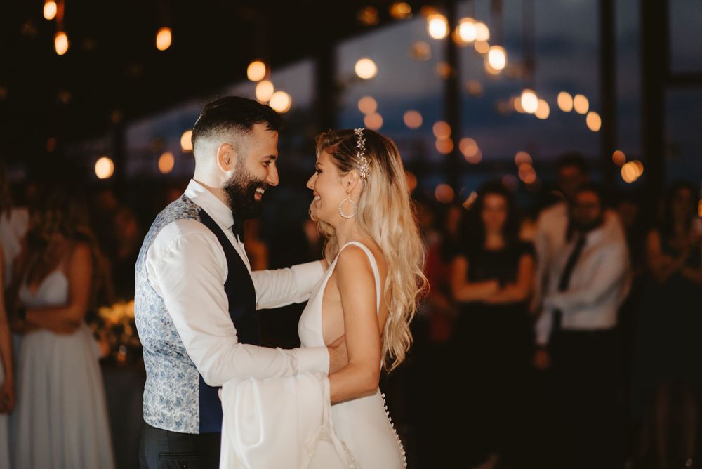 Couple dances intimately at their wedding reception with warm lighting in the background.