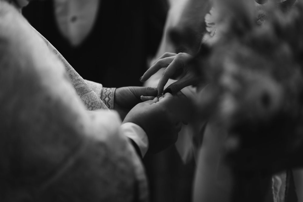 Close-up black and white shot of hands exchanging rings during wedding ceremony.