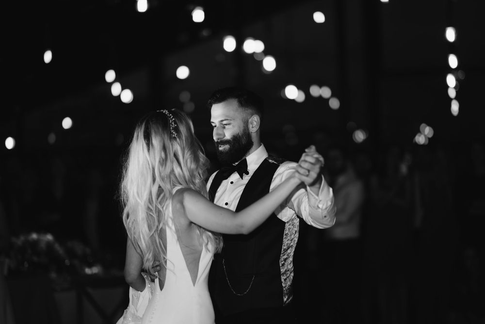 Couple shares their first dance under twinkling lights at an evening wedding reception.
