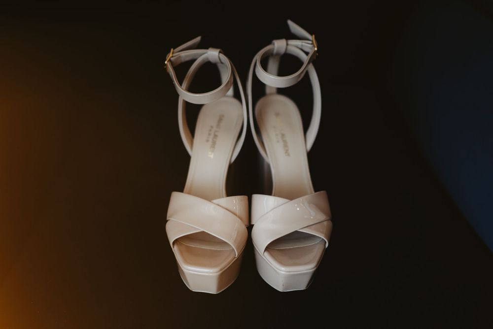 Elegant white platform sandals with ankle straps against dark background.