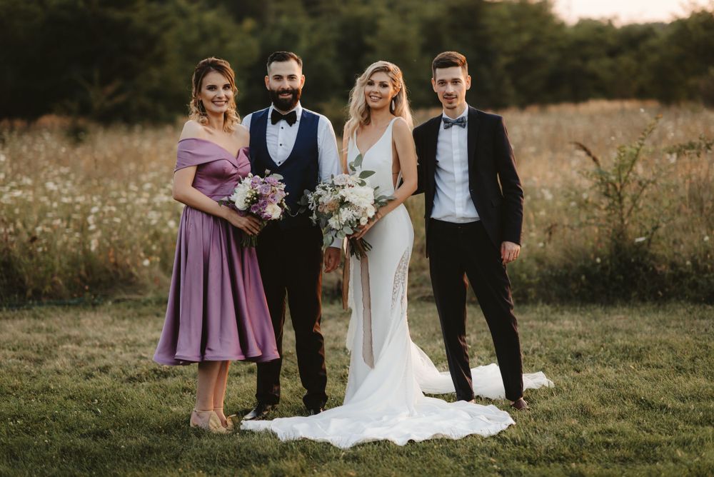 Small wedding party poses together in formal attire during outdoor photo session.