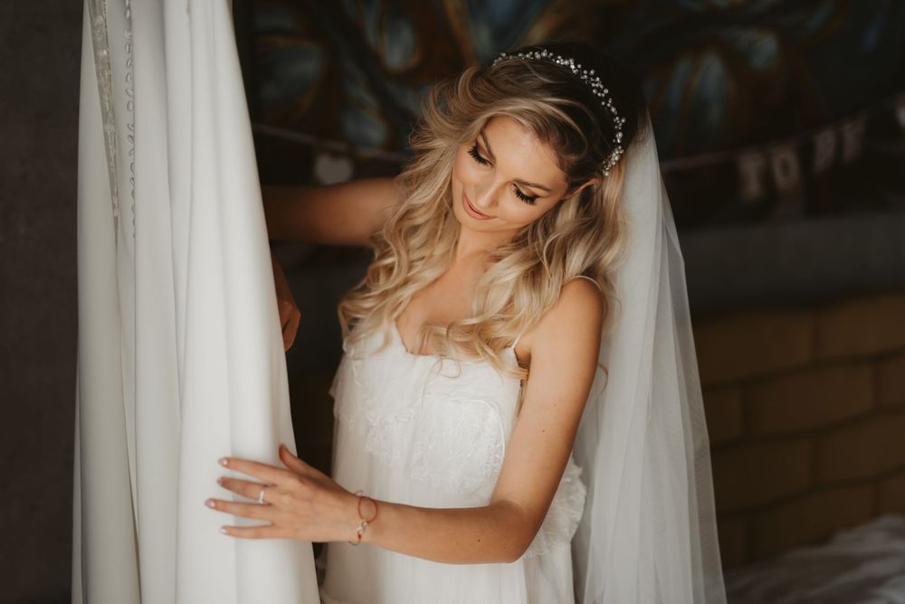 Bride in white dress and veil preparing for wedding ceremony.