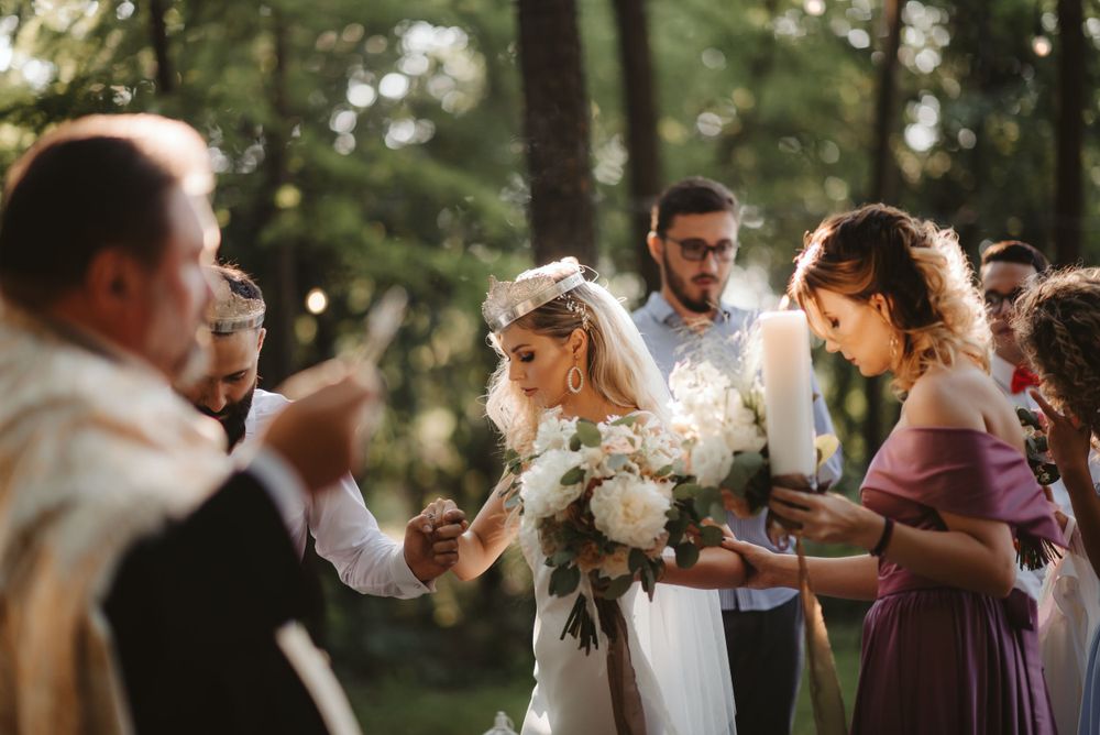 Joyful outdoor wedding ceremony with bridesmaids in purple dresses celebrating in a forest.