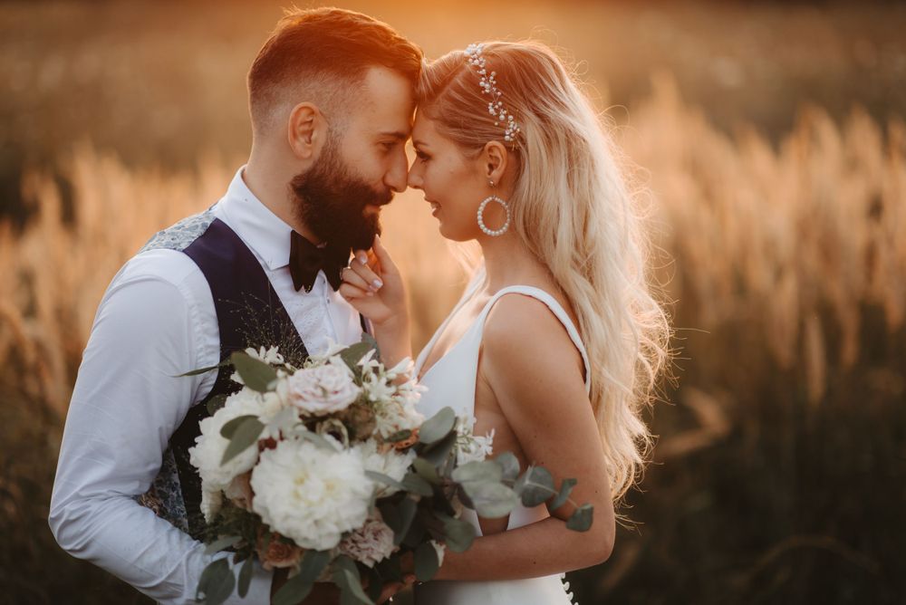 Romantic close-up wedding portrait with white floral bouquet during sunset.
