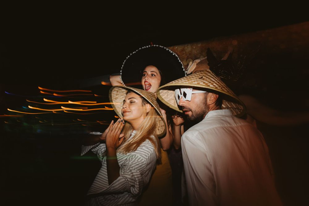 Wedding guests posing dramatically with props in a dark room with light trails.