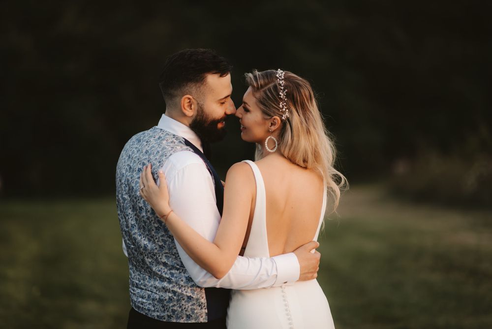 Couple shares intimate moment in formal wedding attire outdoors.
