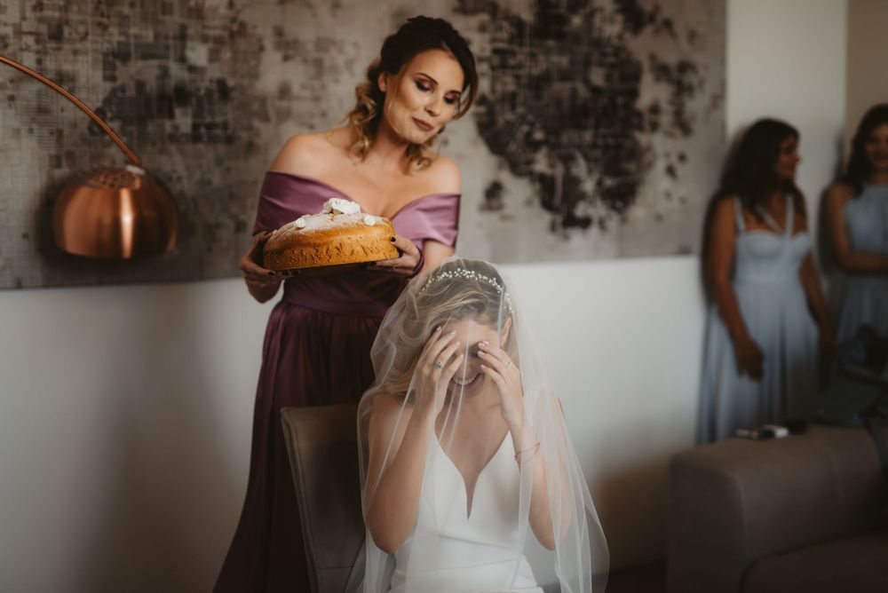 Candid moment of wedding day preparations with bridesmaids in a rustic brick-walled room.