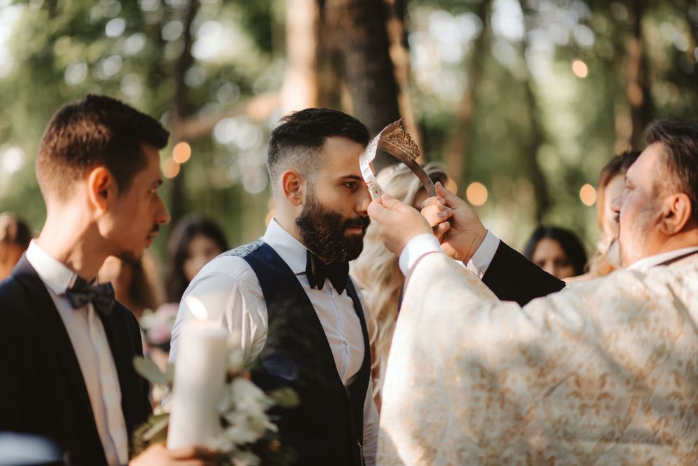 Wedding ceremony attendants sharing an emotional moment in a sunlit forest setting.