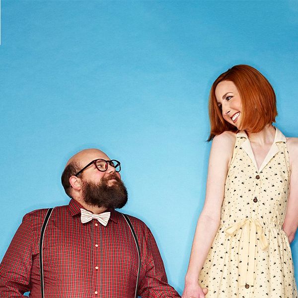 A whimsical studio portrait featuring contrasting heights and styles against a bright blue backdrop.