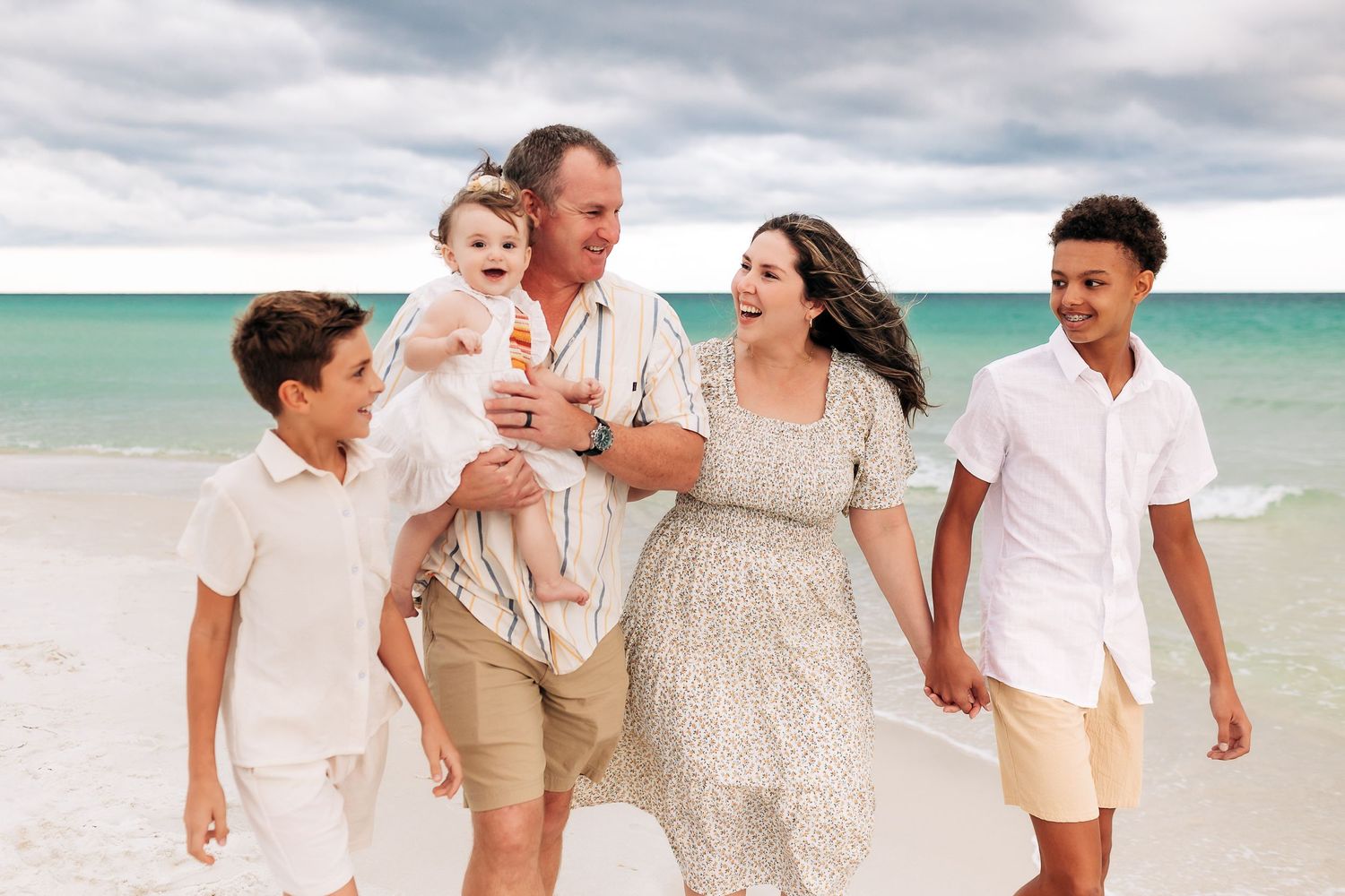 young family cuddling in Navarre Beach at sunset