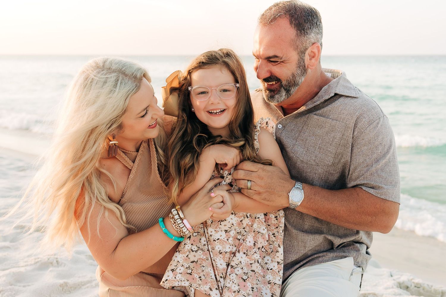 young family cuddling in Navarre Beach  at sunset