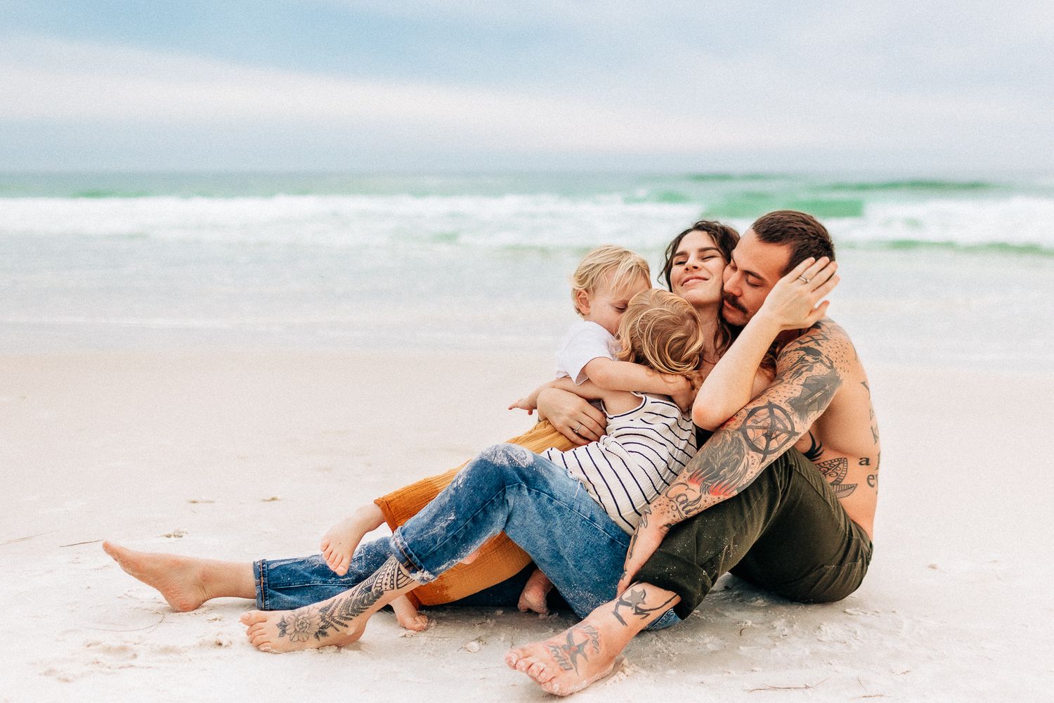 young family cuddling in Navarre Beach  at sunset