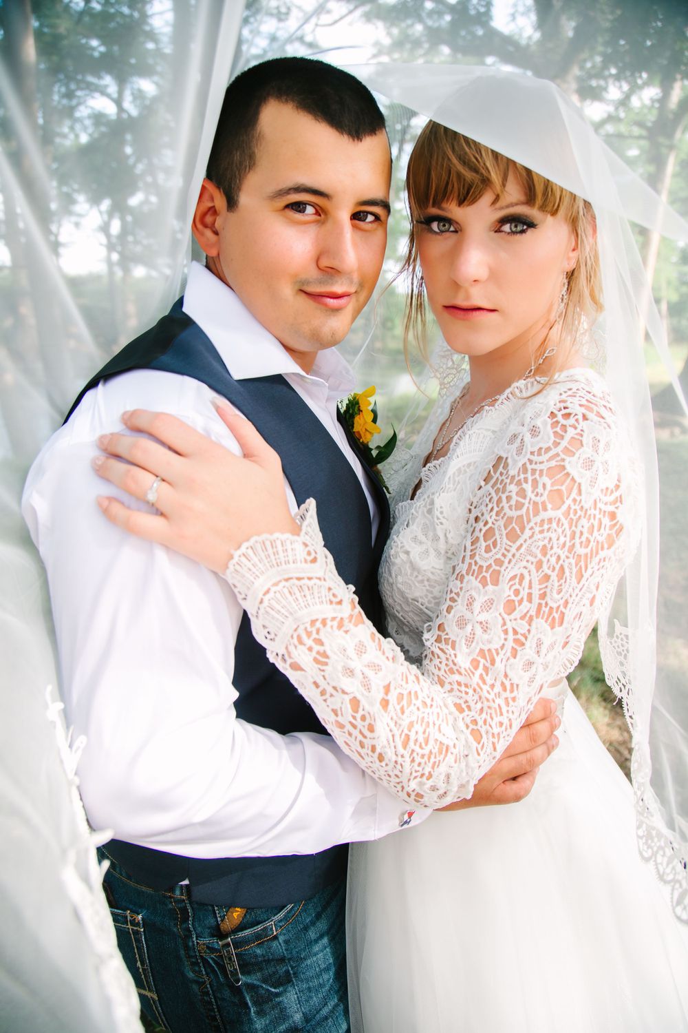 Bride and groom embracing each other under the veil
