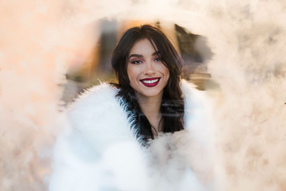 Bridal model smiling with joy through a snowy window