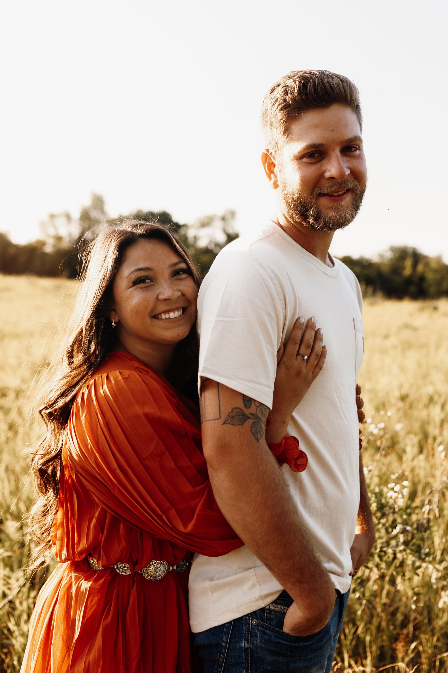 Happy couple embracing in a sunlit meadow during golden hour.