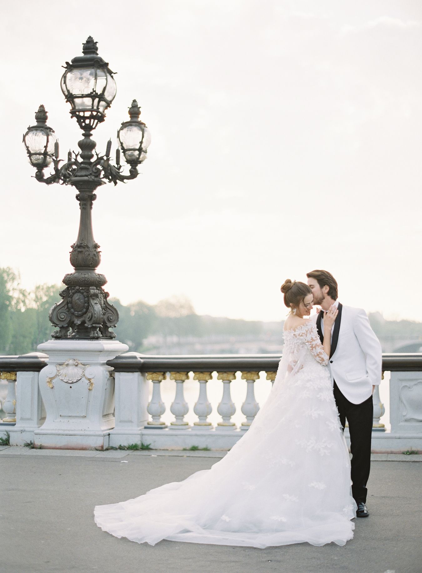 Romantic wedding portrait by ornate vintage lamp post with white balustrade railing.