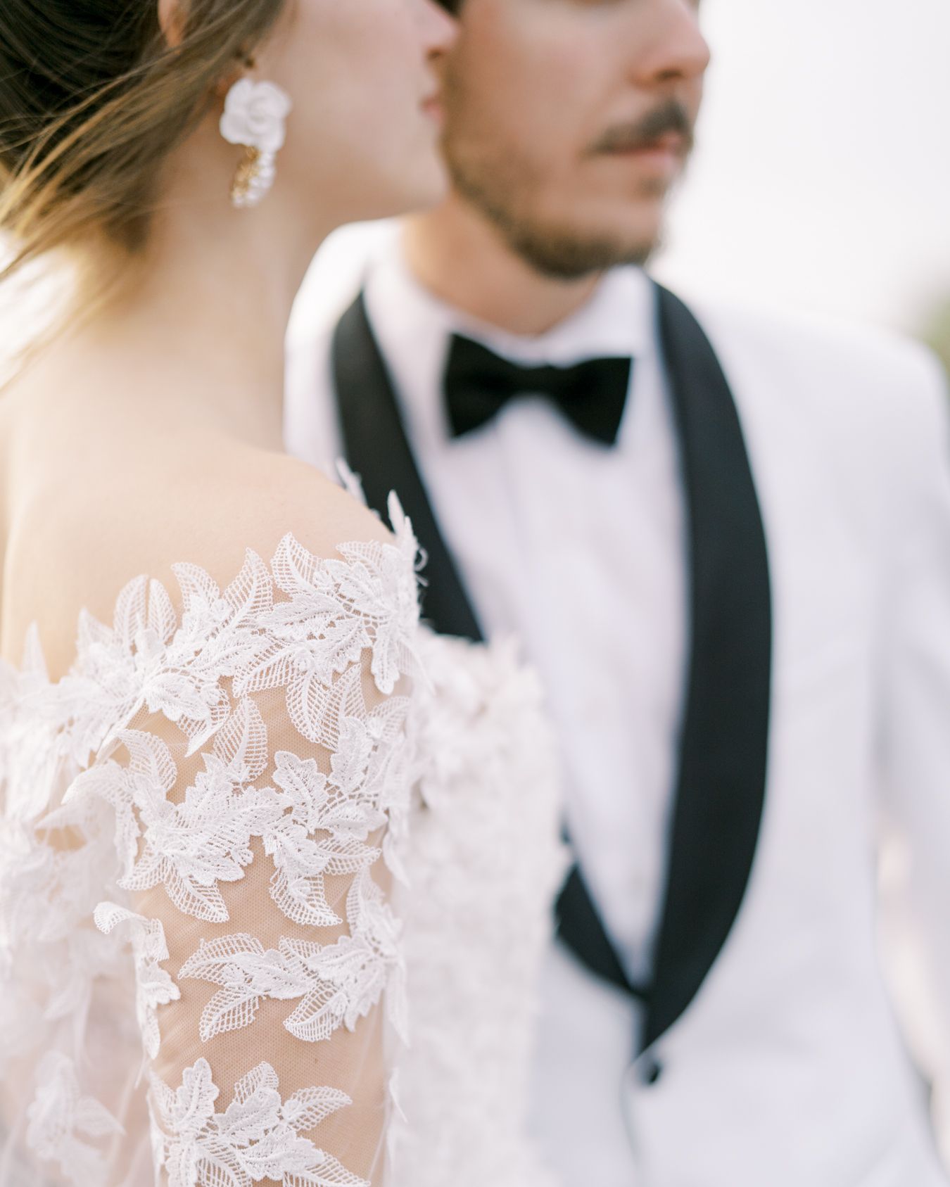 Close-up of elegant wedding attire showing delicate lace details and classic black bow tie.