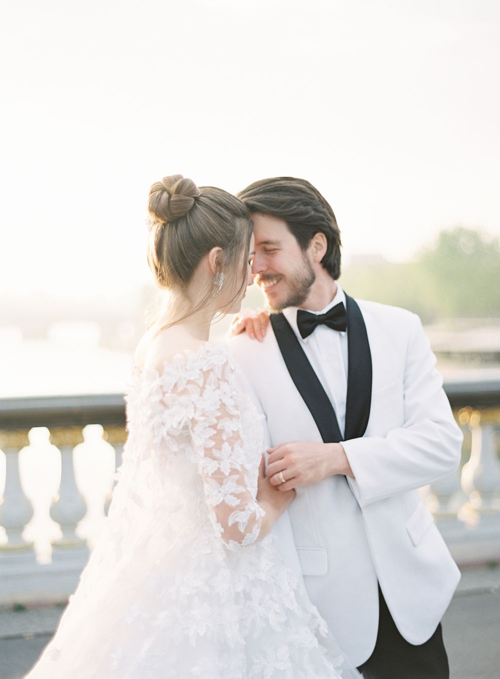 Romantic wedding portrait featuring elegant white tuxedo jacket and lace bridal gown.