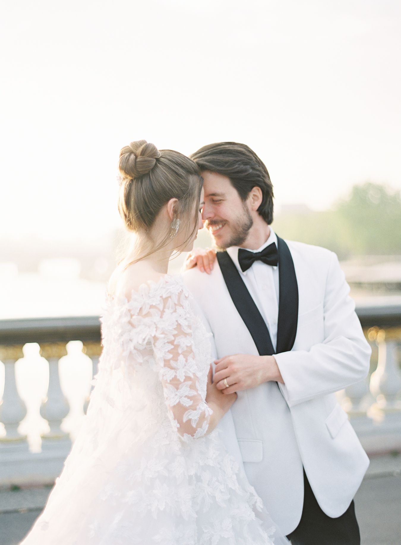 Romantic wedding portrait featuring elegant white tuxedo jacket and lace bridal gown.