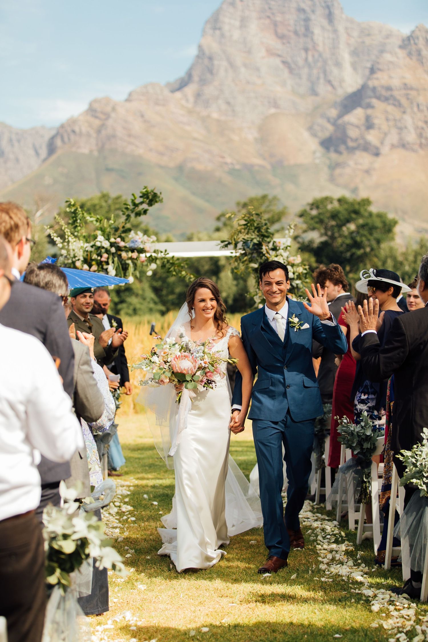 Outdoor wedding ceremony at a scenic mountain venue with white floral decorations lining the aisle path.