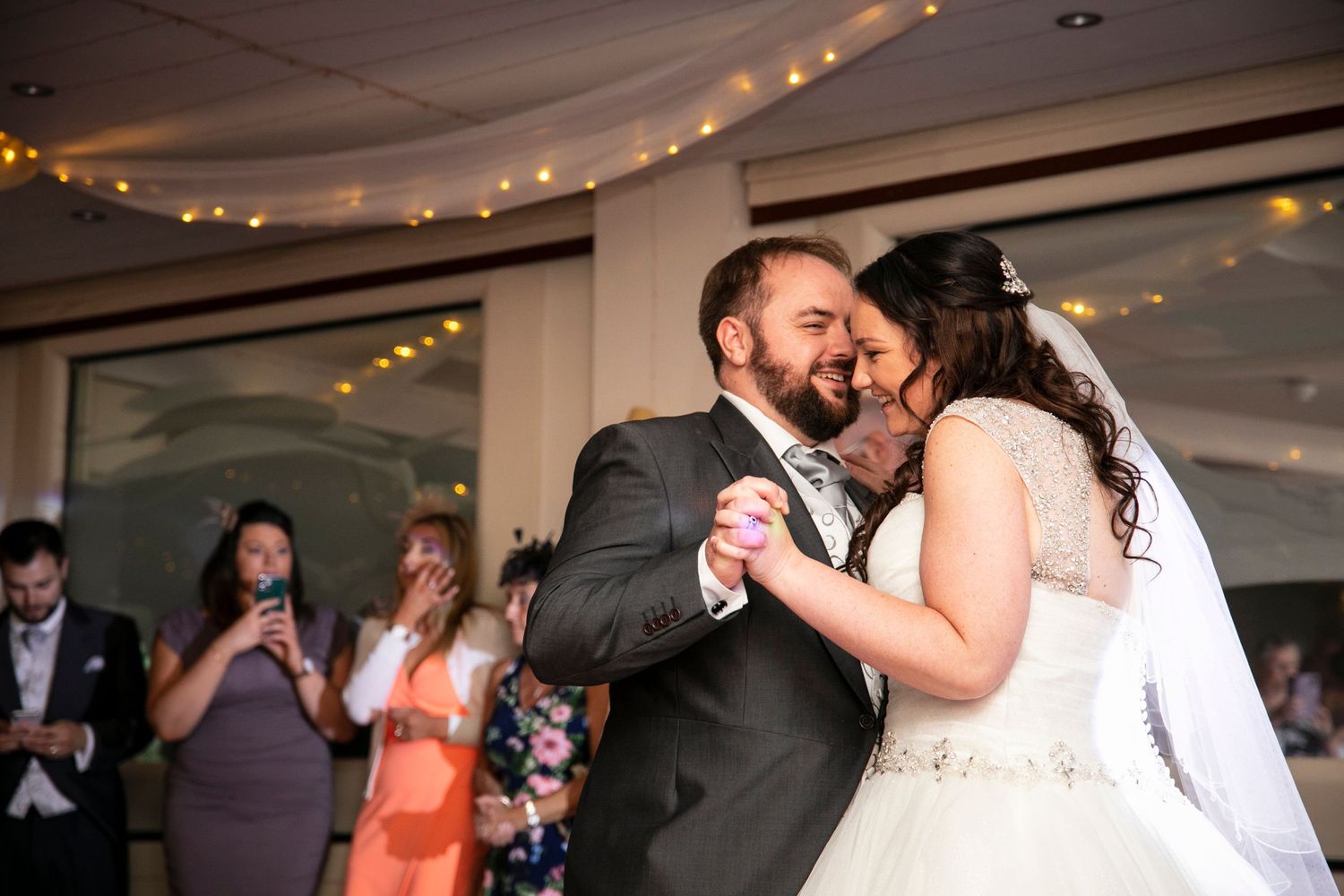 A romantic first dance moment at a wedding reception with string lights overhead.