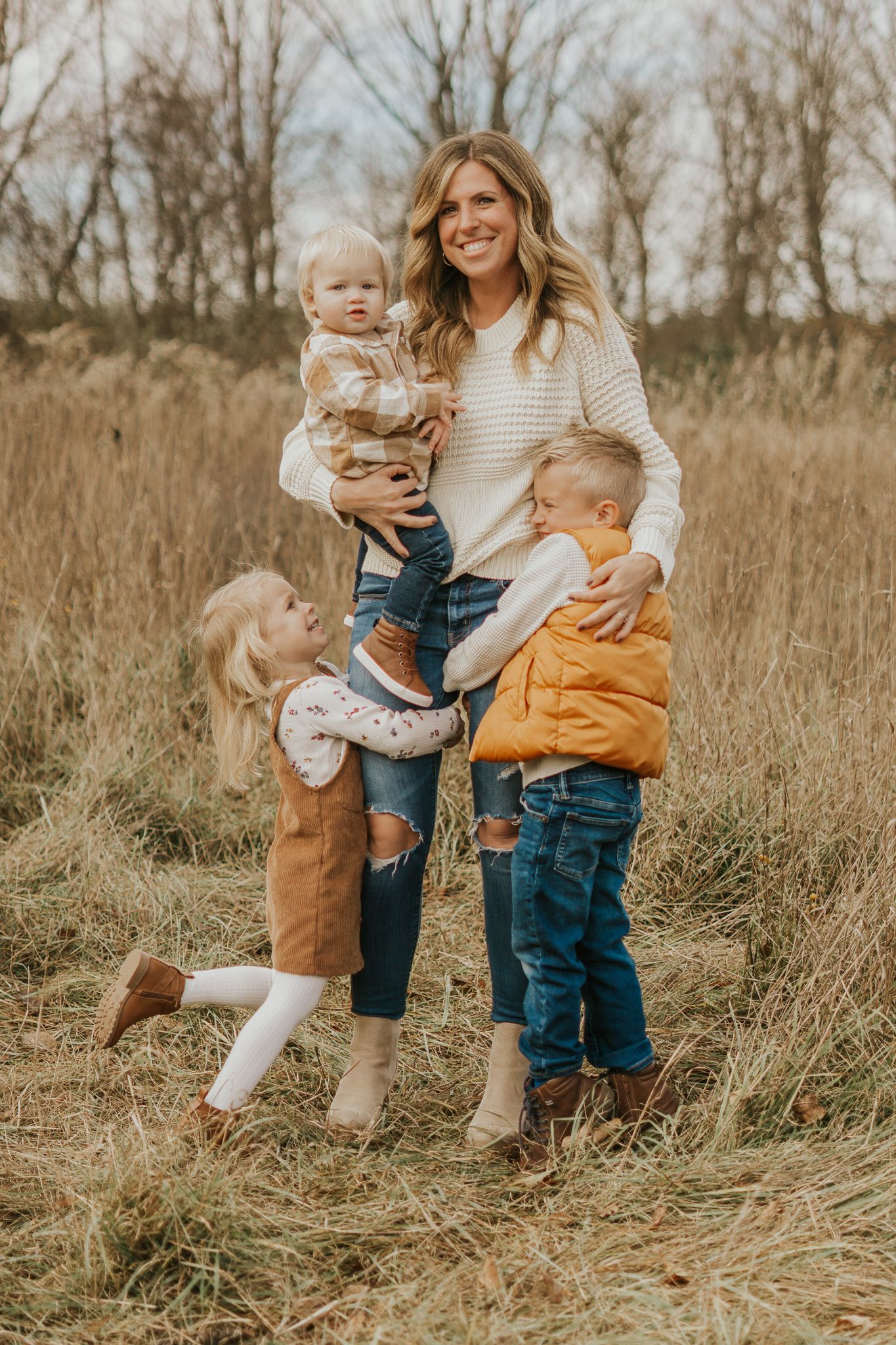 Children playing in tall grass during an autumn photoshoot.