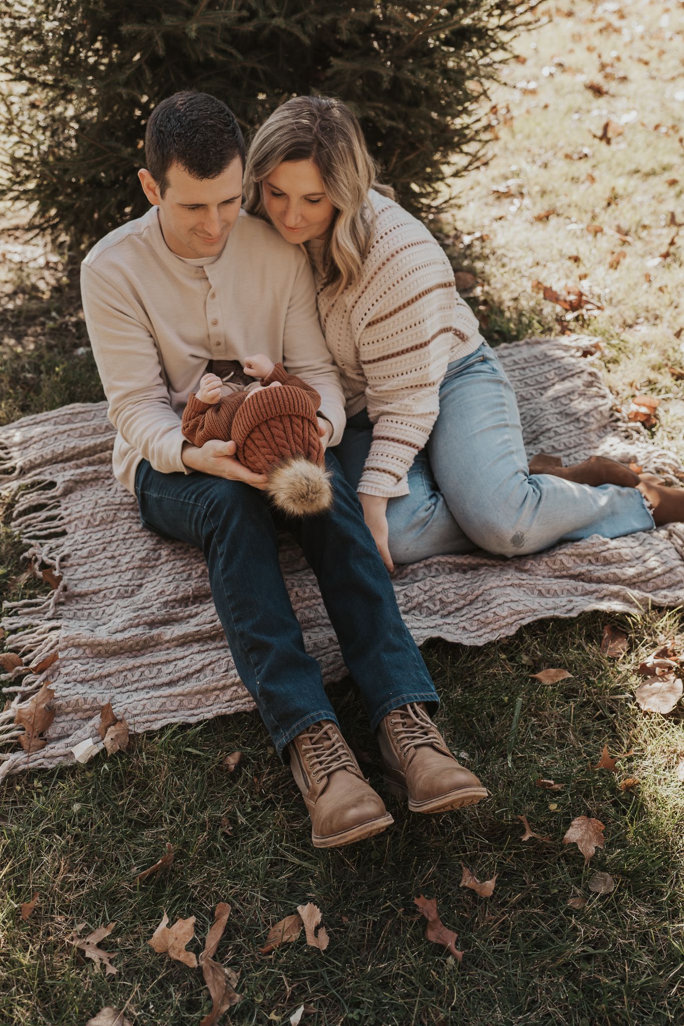 A family relaxes on a blanket during an autumn outdoor photo session.