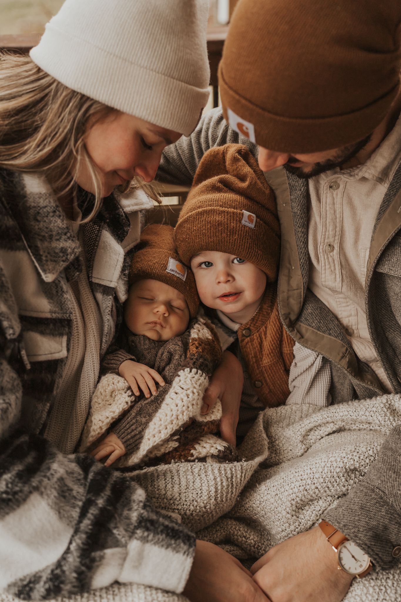 Cozy winter scene with family snuggled together in knit sweaters and beanies, taken by family photographer in home Ann Arbor Michigan.