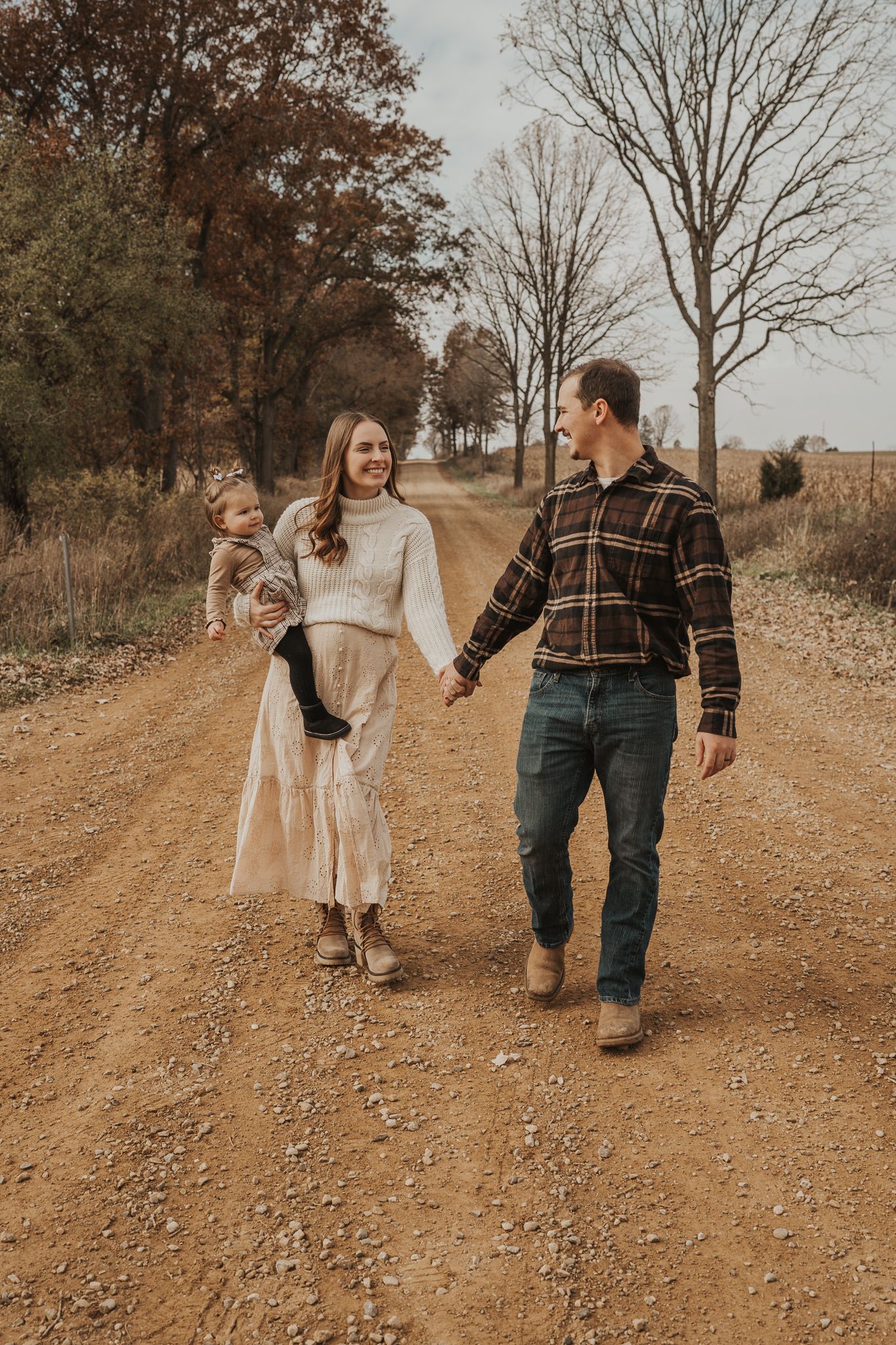 A family takes a stroll together on a gravel country road during golden hour.