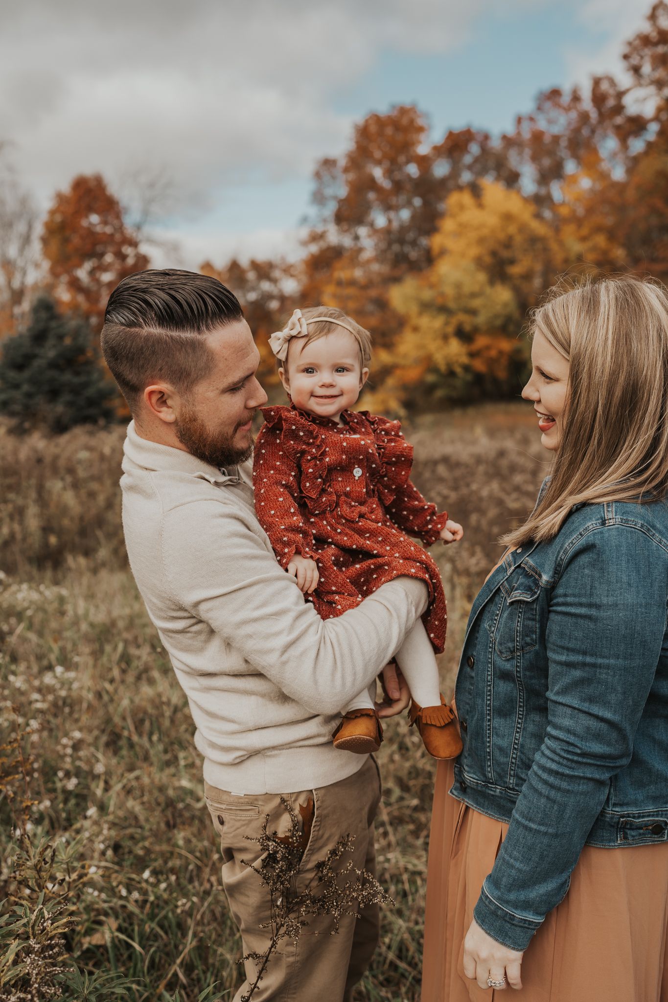 Family portrait session in an autumn field with warm earth tones and fall colors.