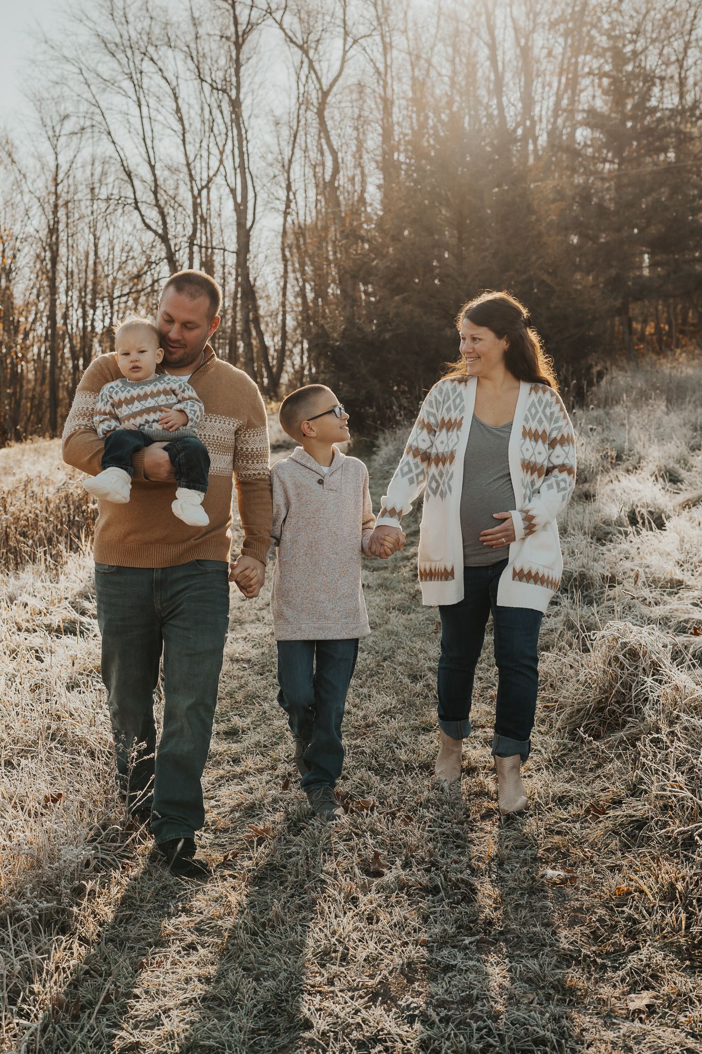 Family walking together through a sunlit field wearing coordinated winter outfits in Michigan.