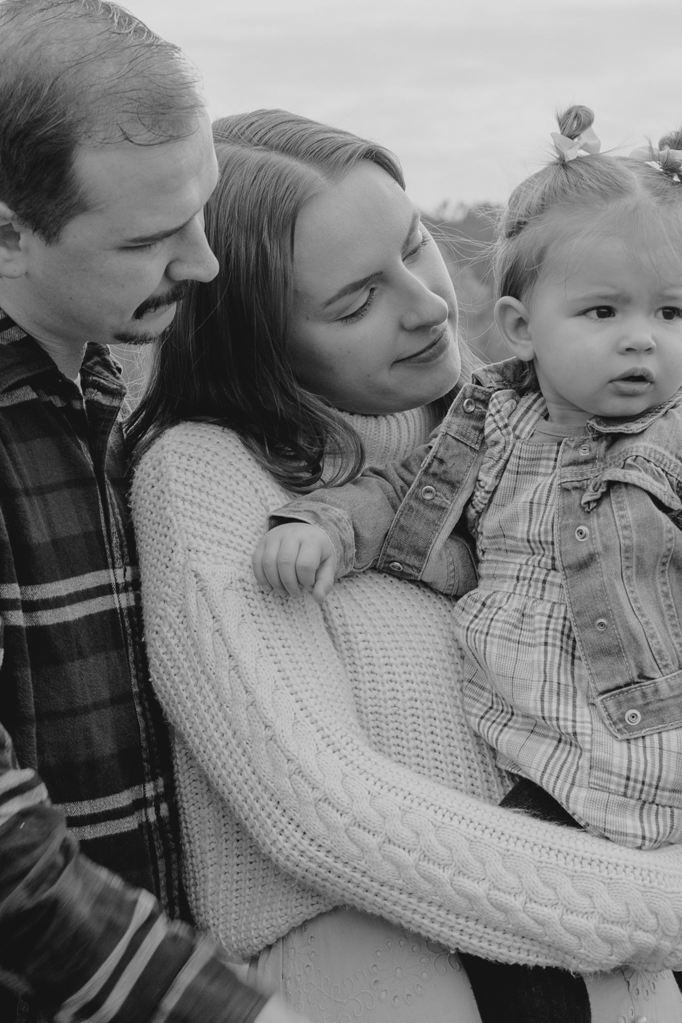An intimate black and white family portrait showing tender moments outdoors.