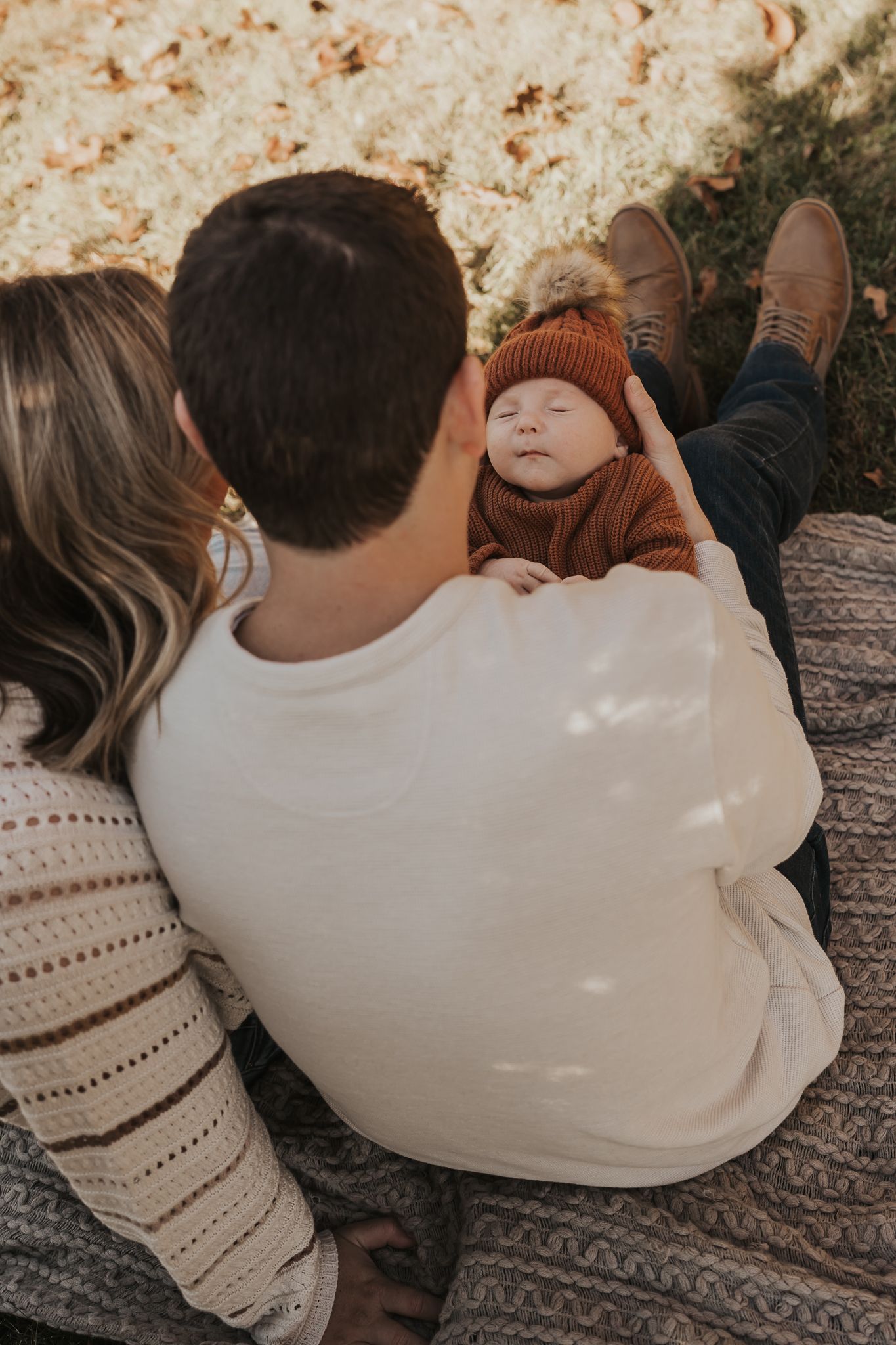 A family cuddles close together on a gray blanket during a Michigan outdoor photo session.
