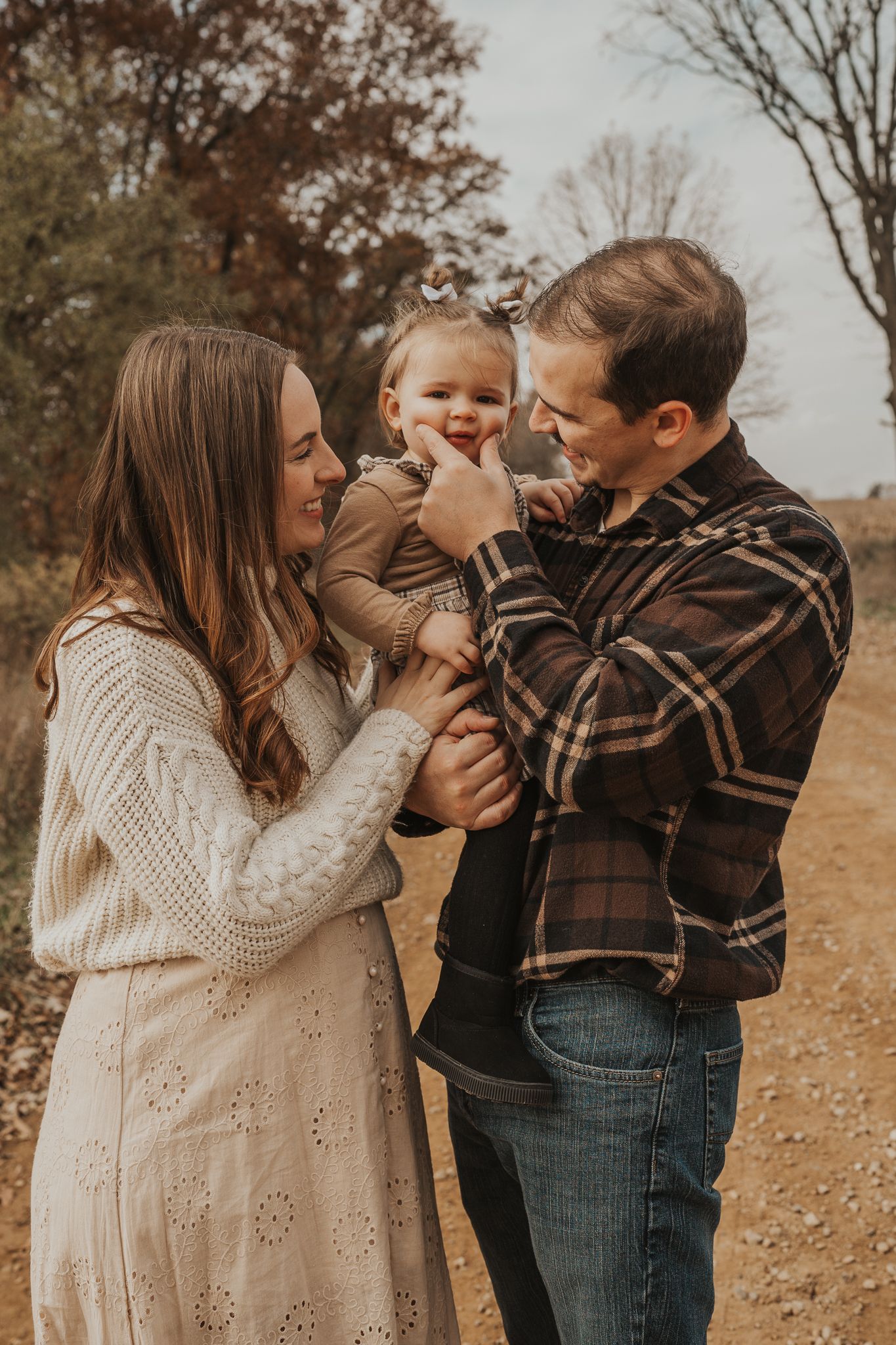 A family in coordinated cream and brown outfits shares playful moments together on a fall day.