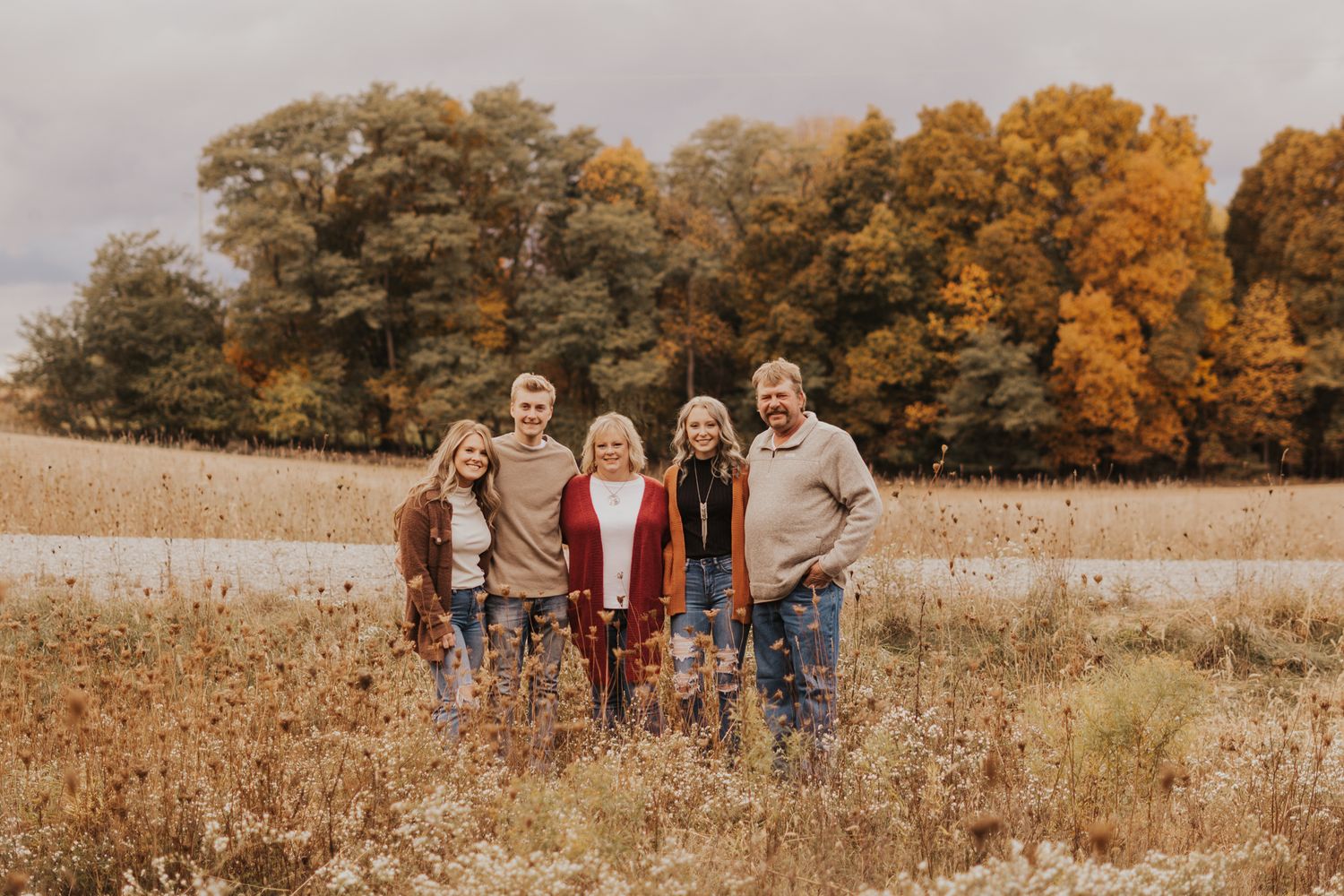 Group portrait in a rustic field with autumn foliage and golden light.
