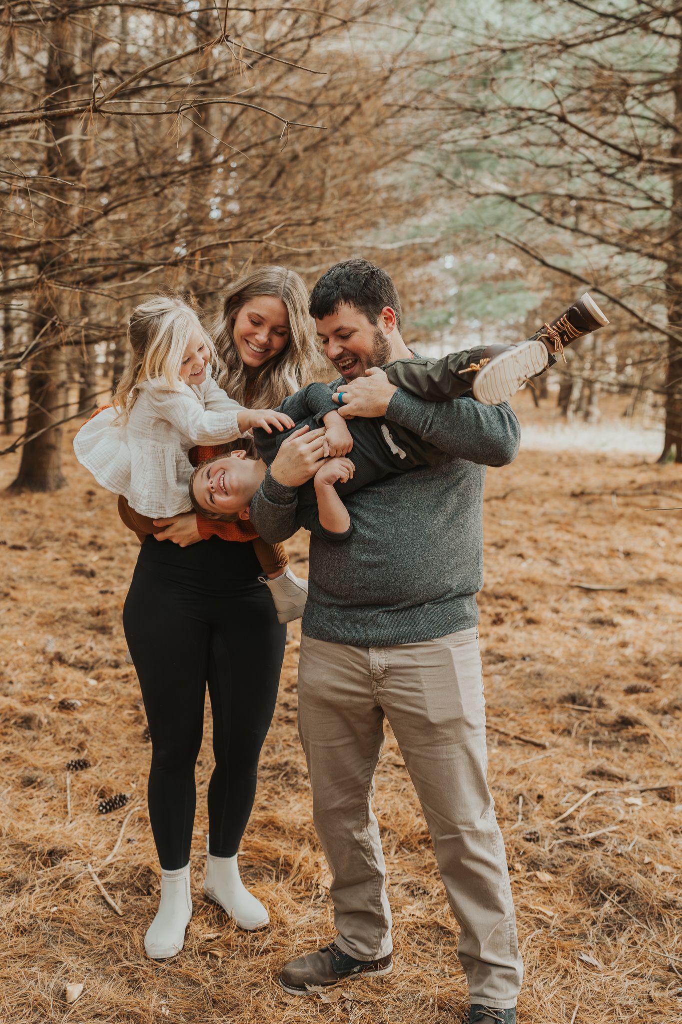 A playful family moment captured in a wooded setting during fall.