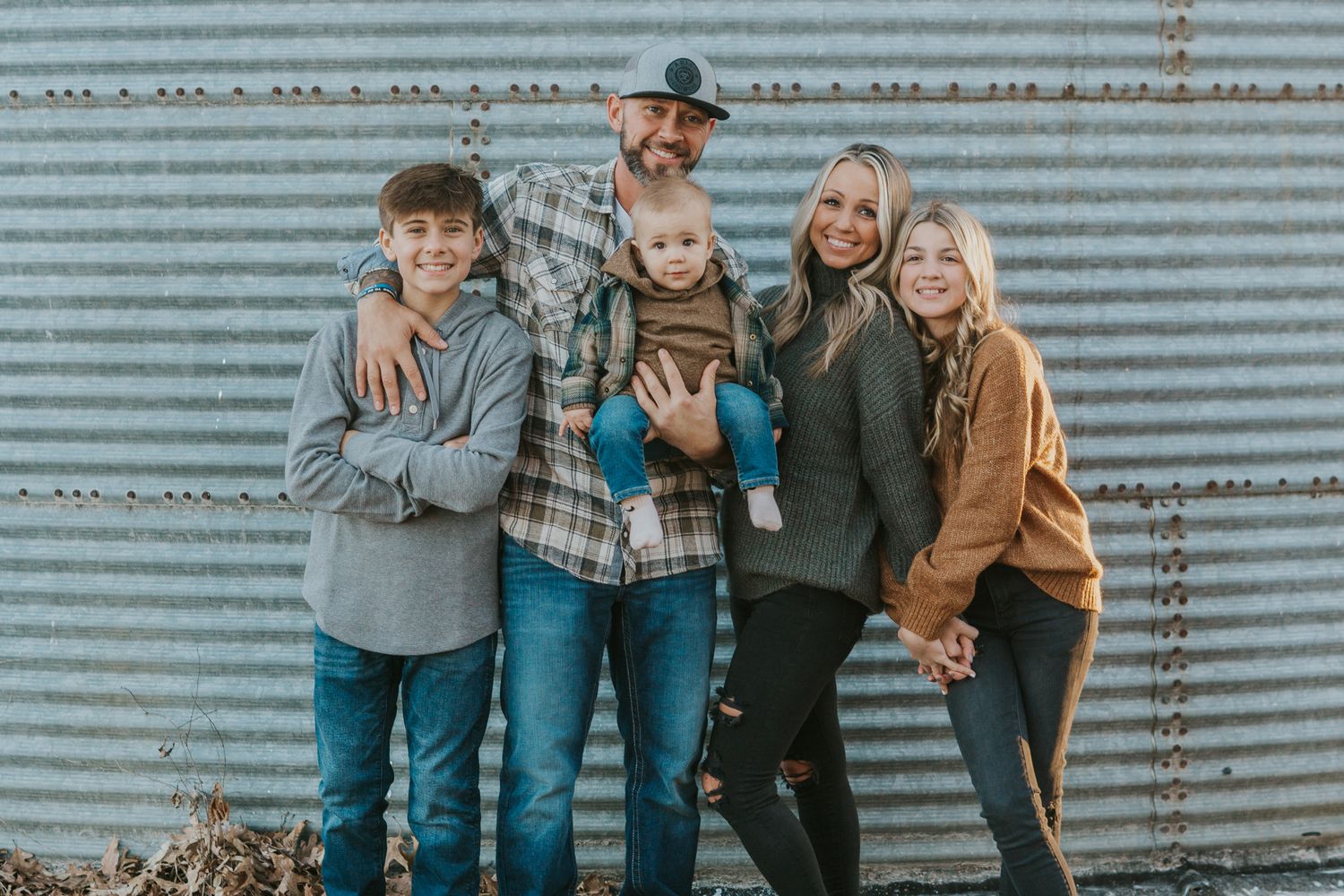 Group photo session in front of a corrugated metal wall outdoors.