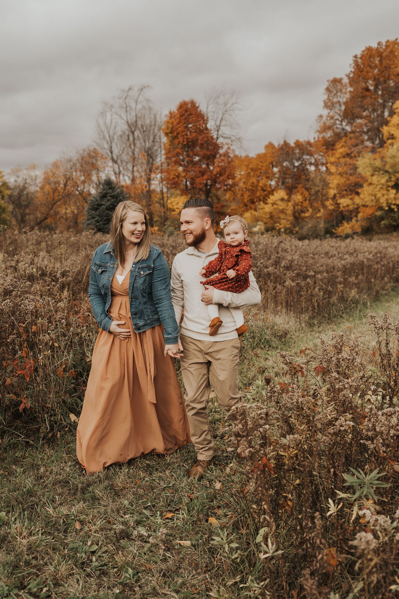 Family enjoying autumn scenery with vibrant orange foliage in the background.