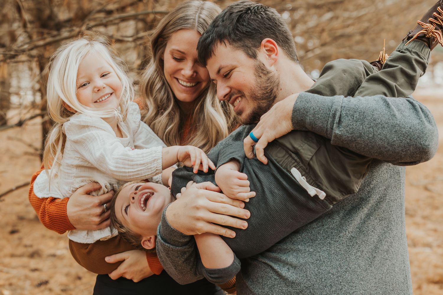 A joyful family laughing and playing together in a forest setting in Spring Arbor Michigan.