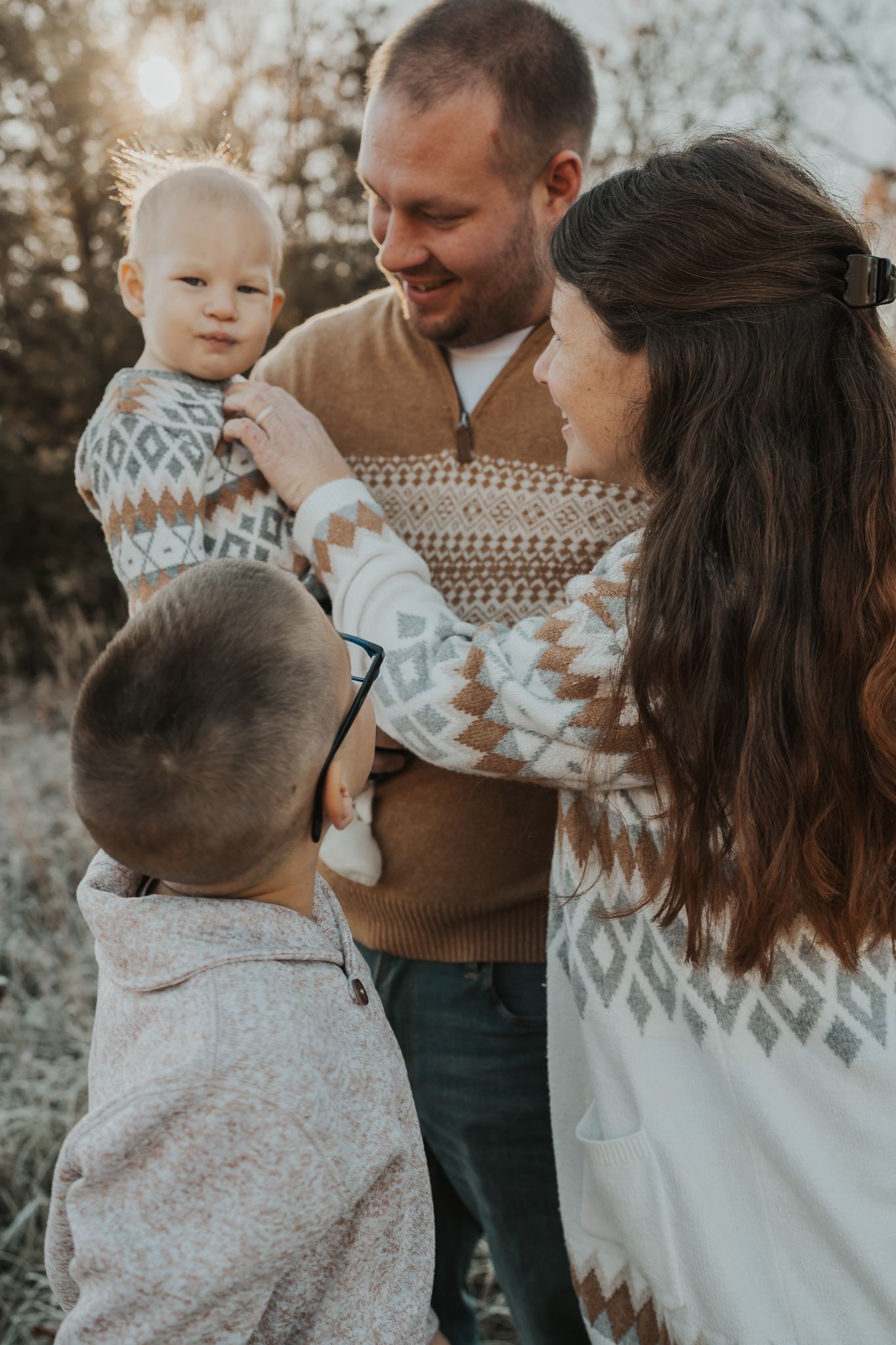 Intimate family moment captured in soft lighting wearing coordinated winter sweaters.