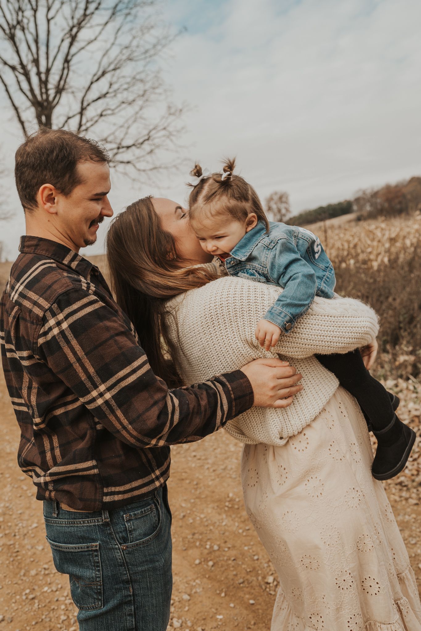 A sweet family moment captured on a rural dirt road during golden hour.
