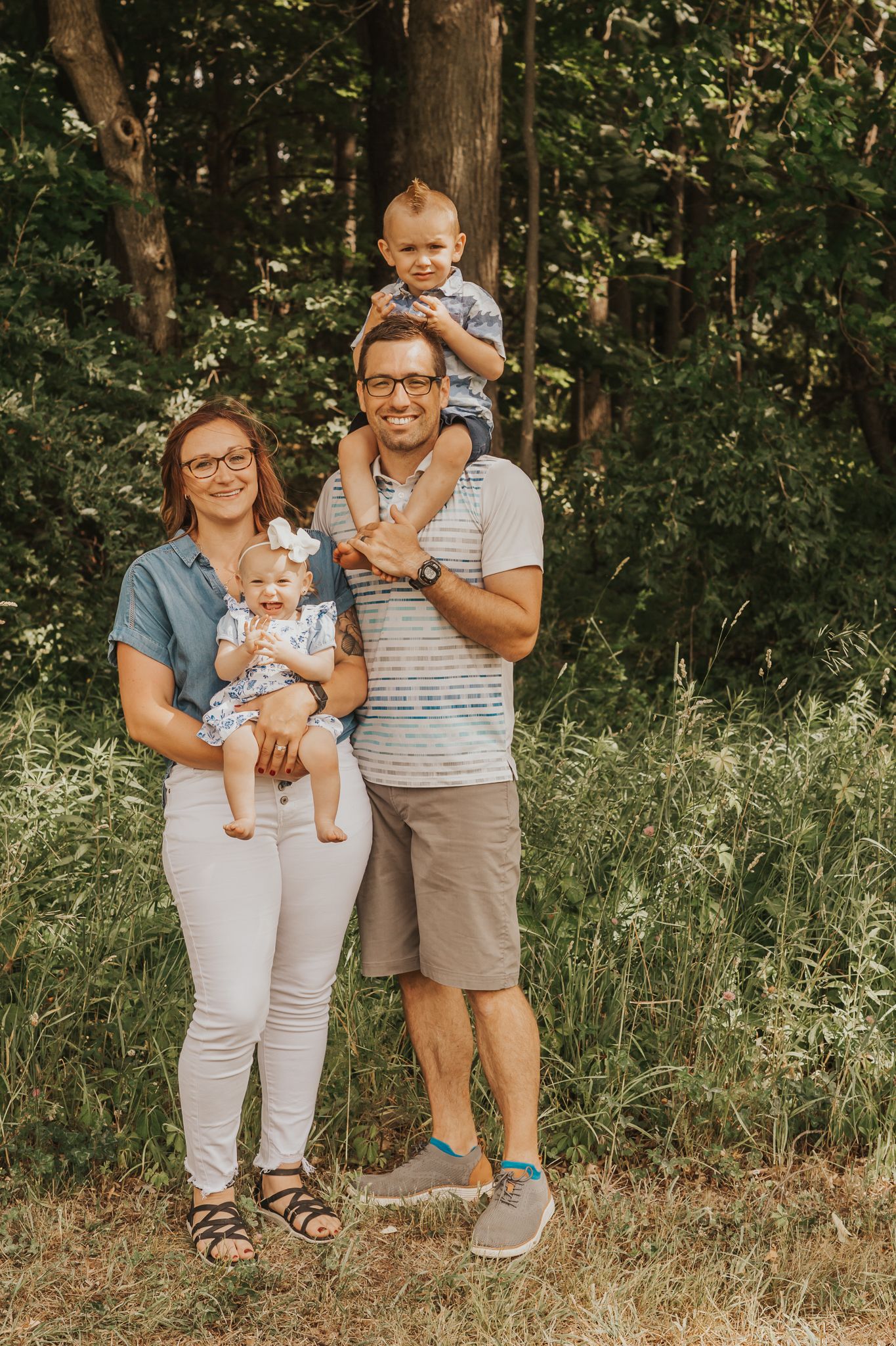 Outdoor family photoshoot in a natural wooded setting during summer.