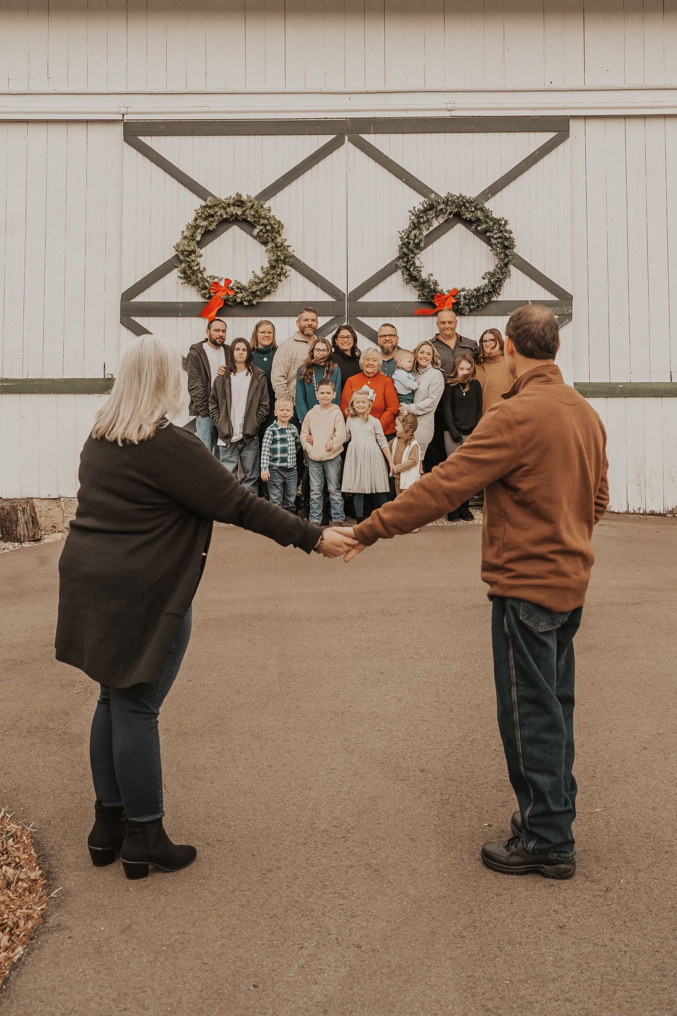 Group photo sequence showing playful interaction between parents with their children in brown and black coats against white barn backdrop.
