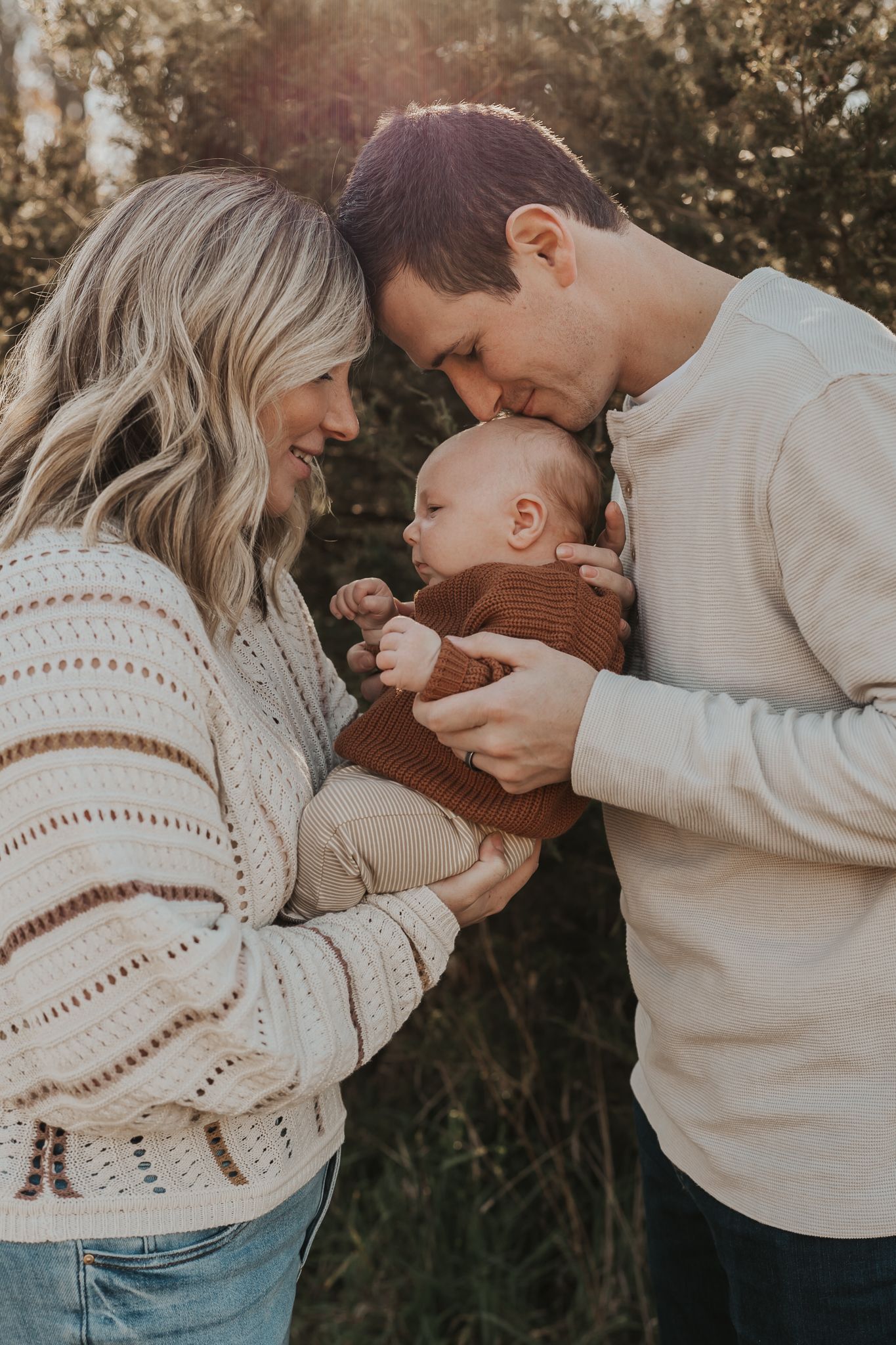 A couple in cozy sweaters shares intimate moments with their baby during an autumn photoshoot.