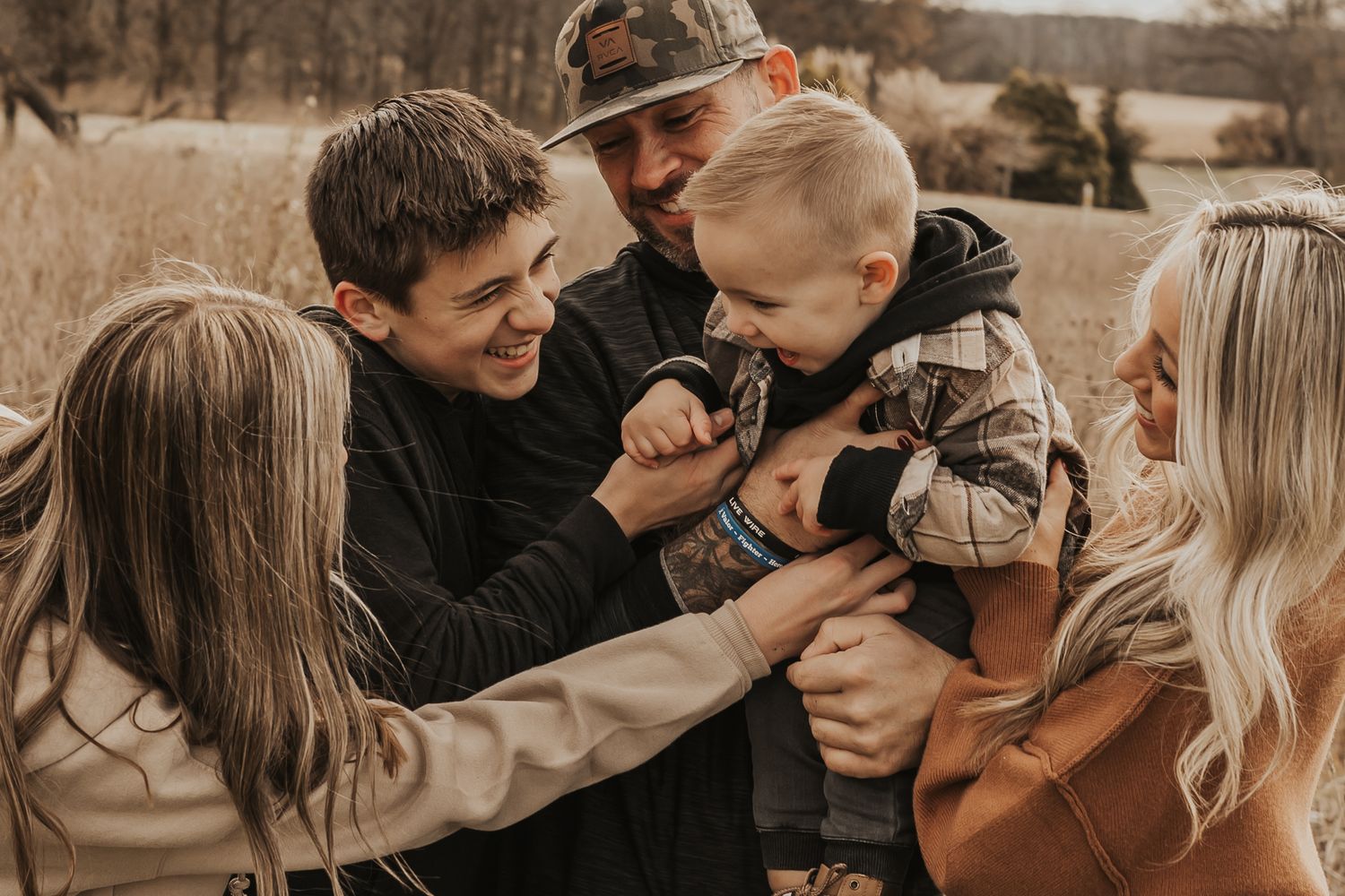 Candid family moment captured in warm sepia tones during outdoor photo session.