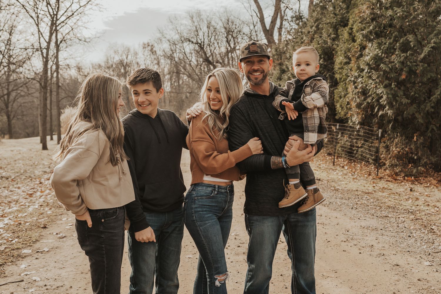 Family of five walking together on a dirt path surrounded by autumn trees outside of Jackson Michigan.