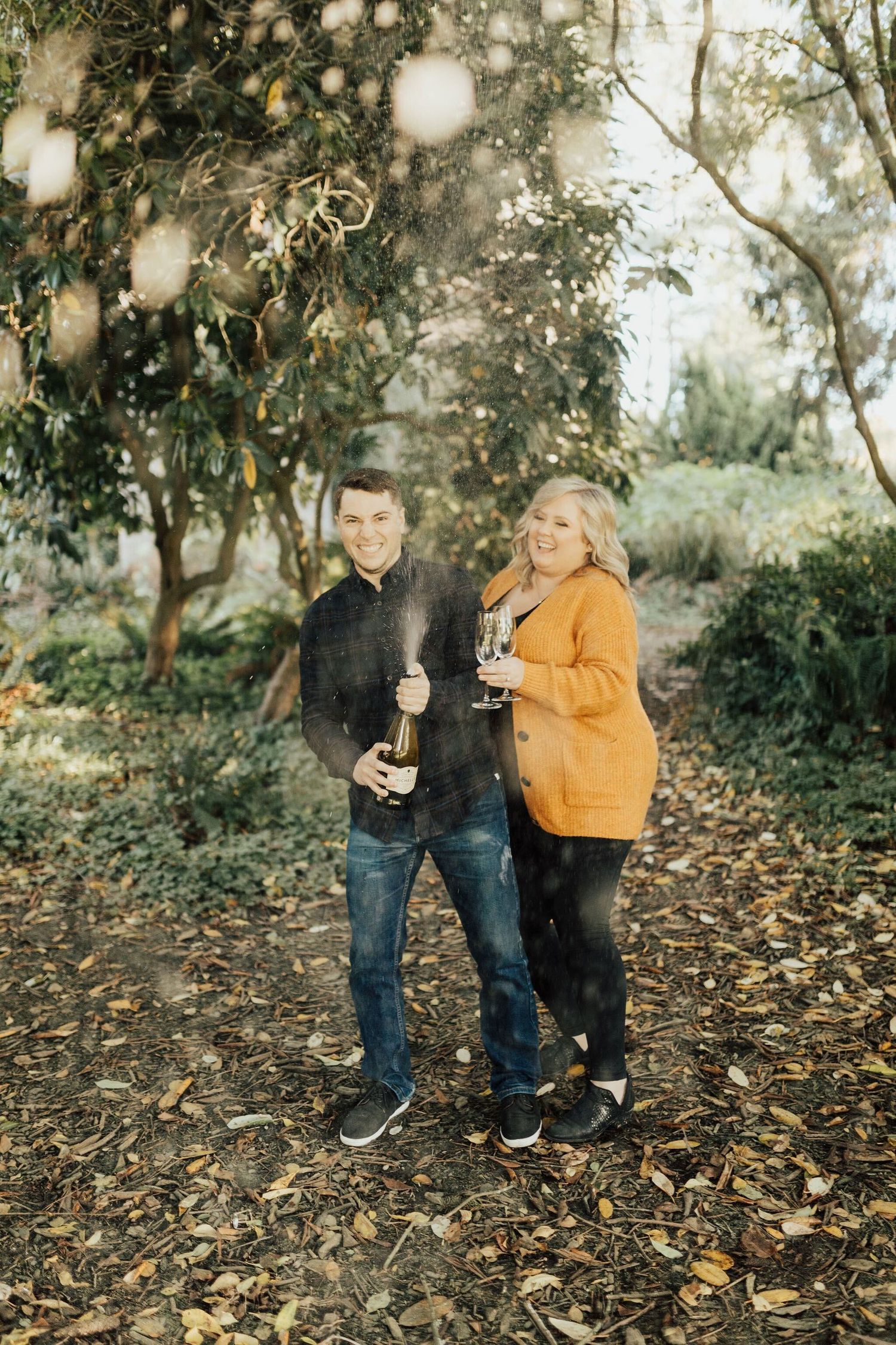 Couple sharing drinks outdoors among fallen autumn leaves and bokeh lighting.