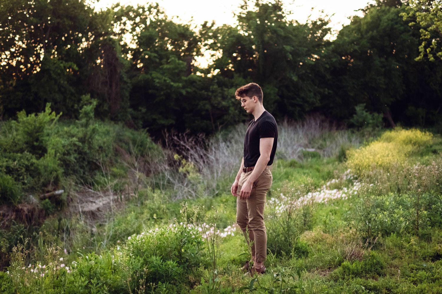 Candid outdoor photoshoot in a natural grassy setting during golden hour.