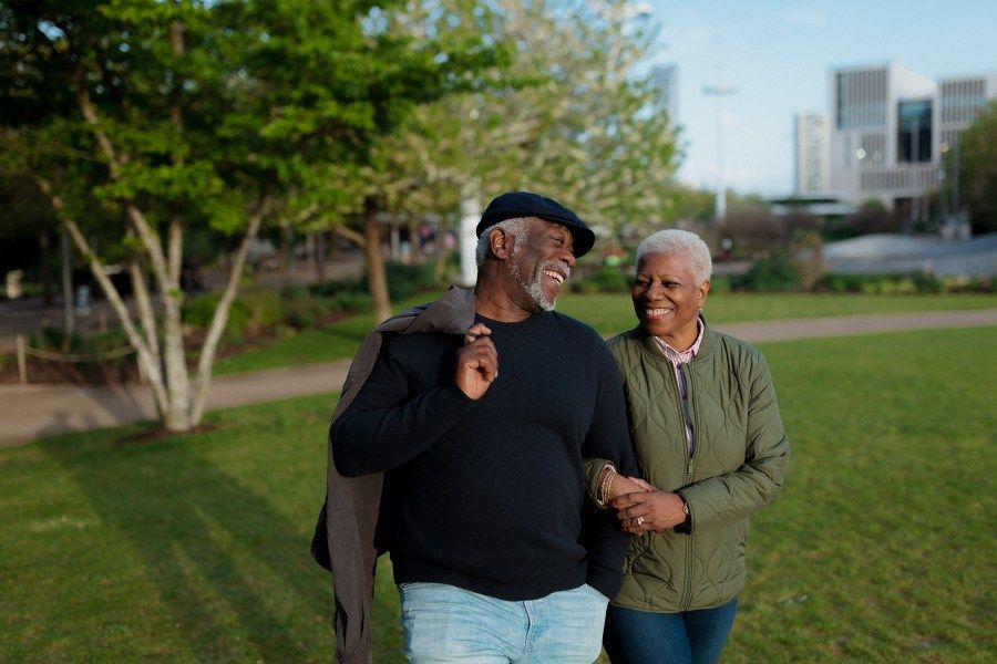 Senior couple walking together on a sunny path in a park.