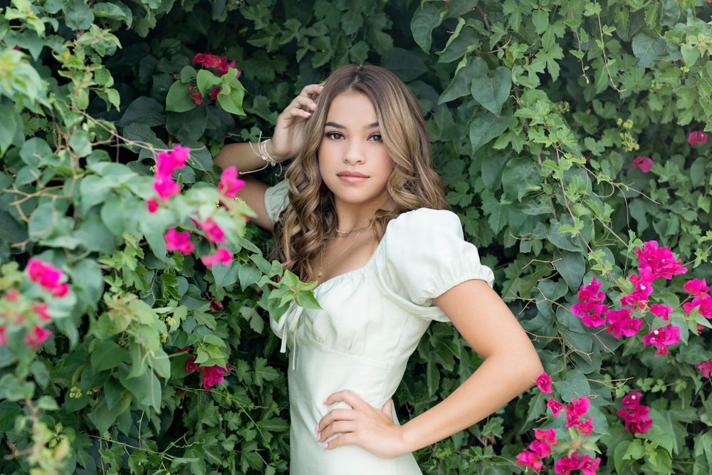 Professional portrait in a garden setting with blooming pink flowers.